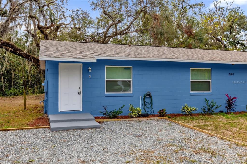 A blue, single-story concrete block building with a white door and a gravel driveway — 2307 MISPAH AVENUE UNIT A + B, LEESBURG, FL