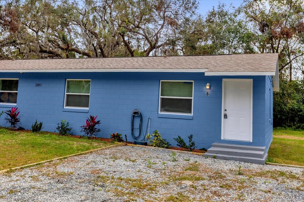 A blue concrete block building features a white door, two windows, and a gravel driveway — 2307 MISPAH AVENUE UNIT A + B, LEESBURG, FL