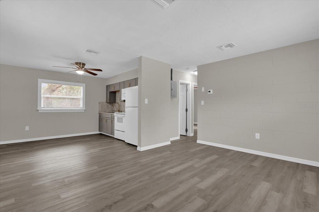 An open-concept room features gray wood-look flooring, a small kitchen area, and a ceiling fan — 2307 MISPAH AVENUE UNIT A + B, LEESBURG, FL