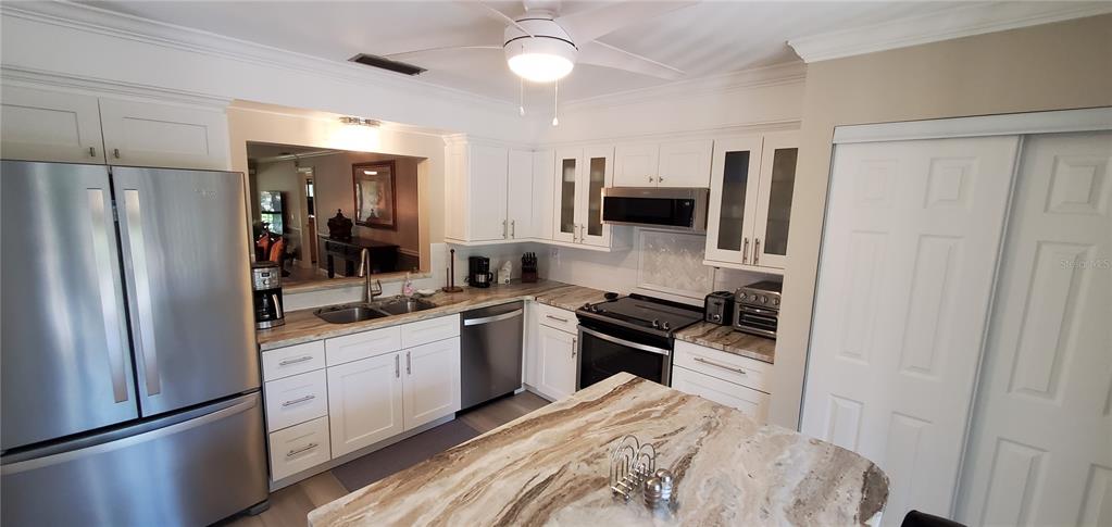 A kitchen features white cabinets, stainless steel appliances, and a marble-patterned island countertop — 6110 COUNTRY CLUB WAY UNIT 201, SARASOTA, FL