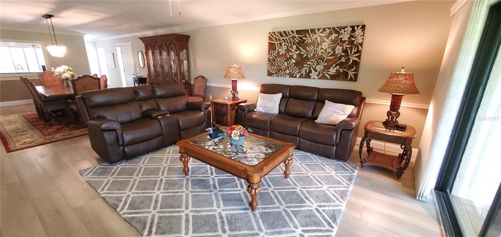 A living room features two brown leather sofas, a coffee table, and a dining area — 6110 COUNTRY CLUB WAY UNIT 201, SARASOTA, FL