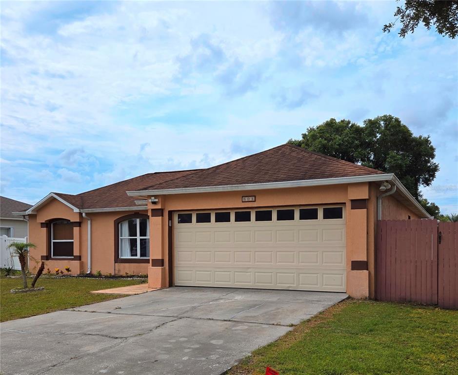A single-story house with a tan stucco exterior, a two-car garage, and a brown roof — 804 CARROUSEL LANE, KISSIMMEE, FL