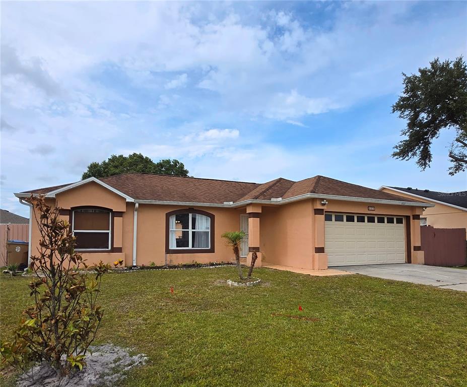 A single-story peach-colored house with a brown roof and an attached two-car garage — 804 CARROUSEL LANE, KISSIMMEE, FL