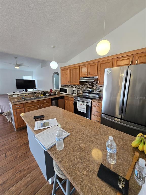 A kitchen with wood cabinets, stainless steel appliances, and a large island with seating — 804 CARROUSEL LANE, KISSIMMEE, FL