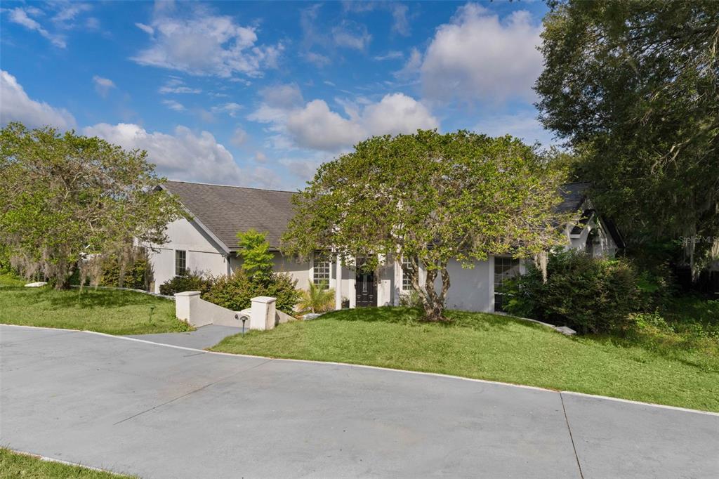 A single-story house with a gray roof and a paved driveway sits behind a lawn — 34415 KINGFISH STREET, FRUITLAND PARK, FL