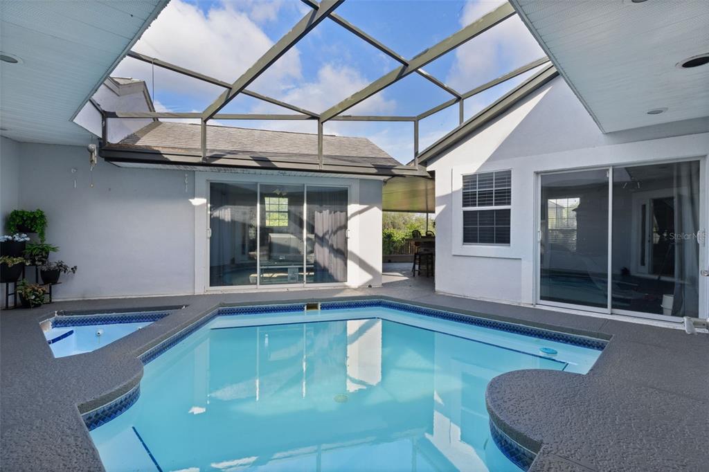 A screened-in patio features a swimming pool and spa surrounded by a concrete deck — 34415 KINGFISH STREET, FRUITLAND PARK, FL