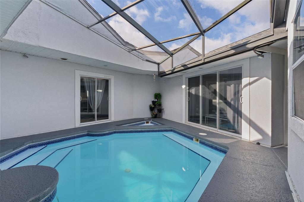 A screened-in pool area features a blue-tiled swimming pool and sliding glass doors — 34415 KINGFISH STREET, FRUITLAND PARK, FL