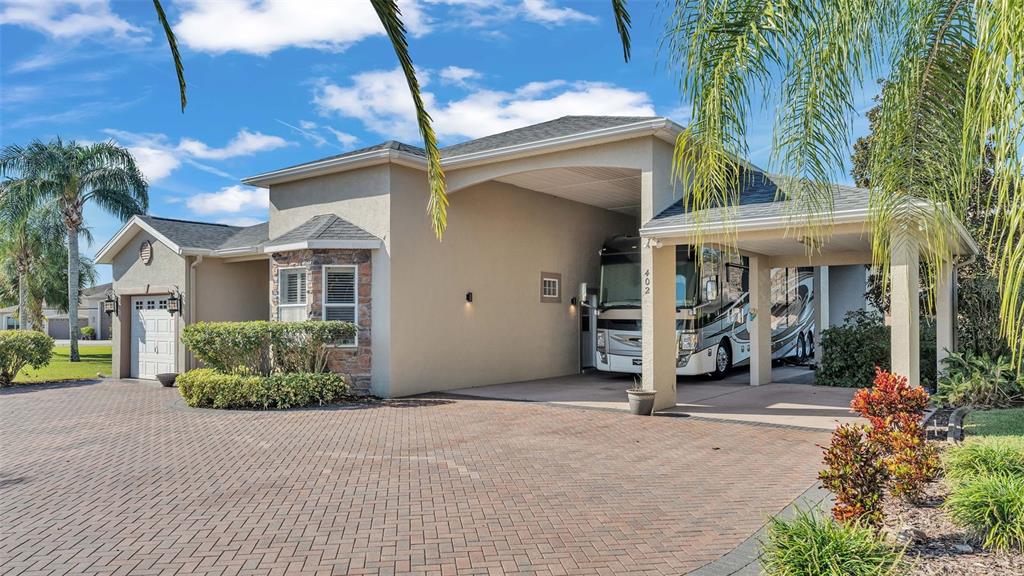 A house exterior features a brick driveway, a small garage, and a large RV carport — 402 CRUISERS DRIVE, POLK CITY, FL