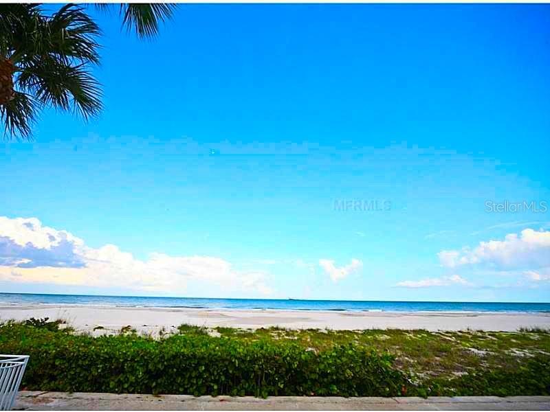 A view of a sandy beach and the ocean from behind a green hedge — 3400 GULF BOULEVARD UNIT 108, BELLEAIR BEACH, FL