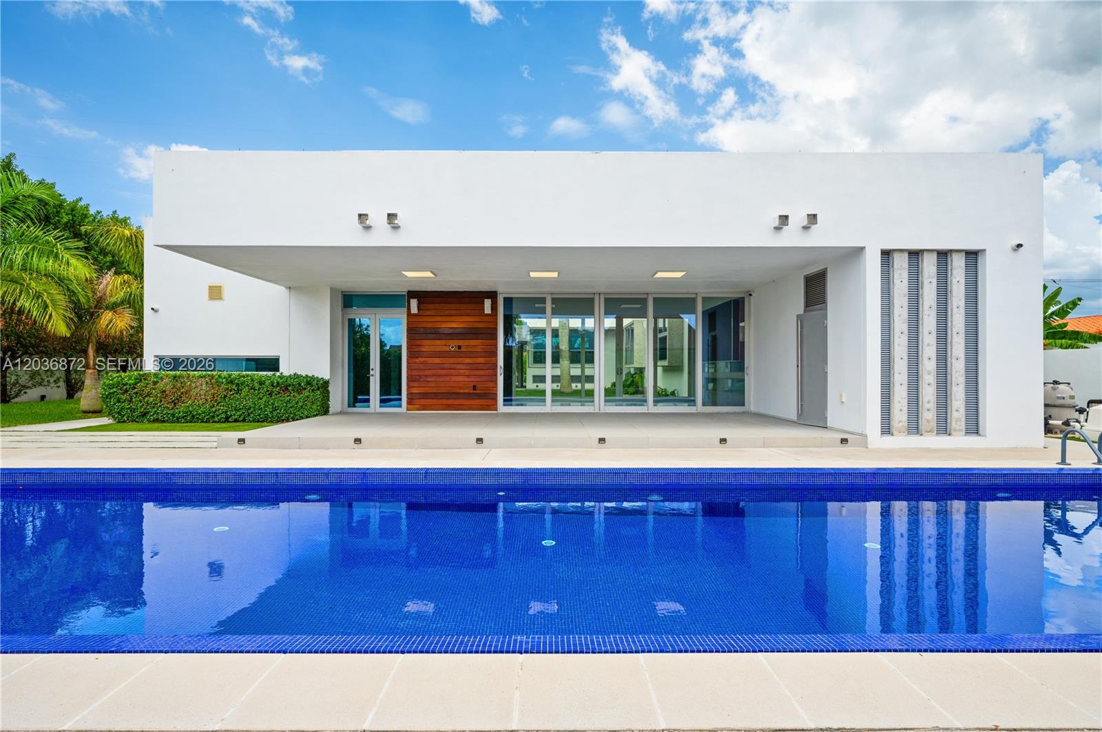 A modern white house exterior features a large swimming pool and a covered patio area — 2360 SW 139th Ave, Miami FL 33175, MIAMI, FL