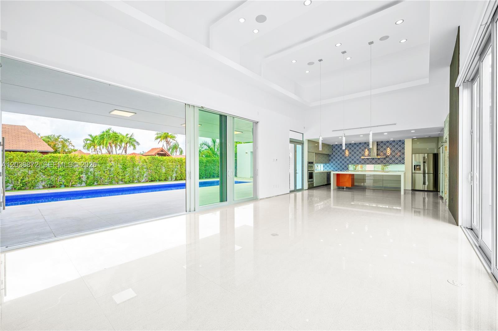 A bright, open-concept living area features white tile floors, a modern kitchen, and sliding glass doors — 2360 SW 139th Ave, Miami FL 33175, MIAMI, FL