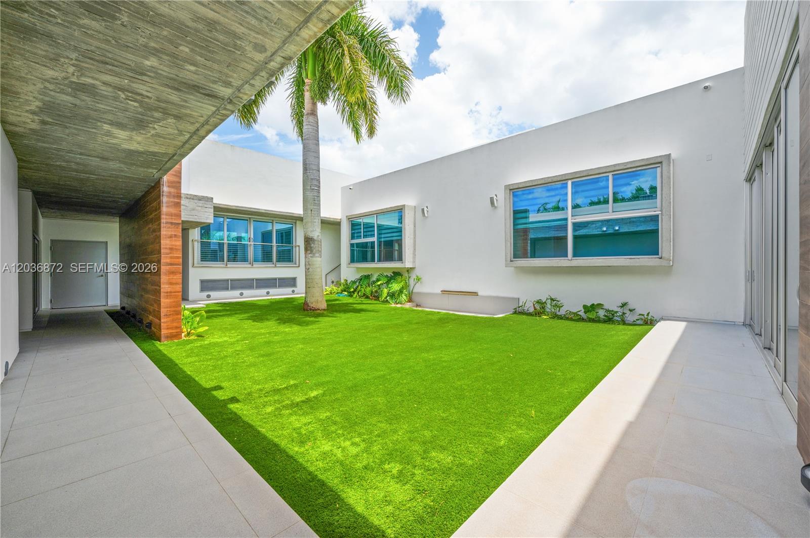 A modern courtyard features a central palm tree, artificial turf, and white exterior walls — 2360 SW 139th Ave, Miami FL 33175, MIAMI, FL