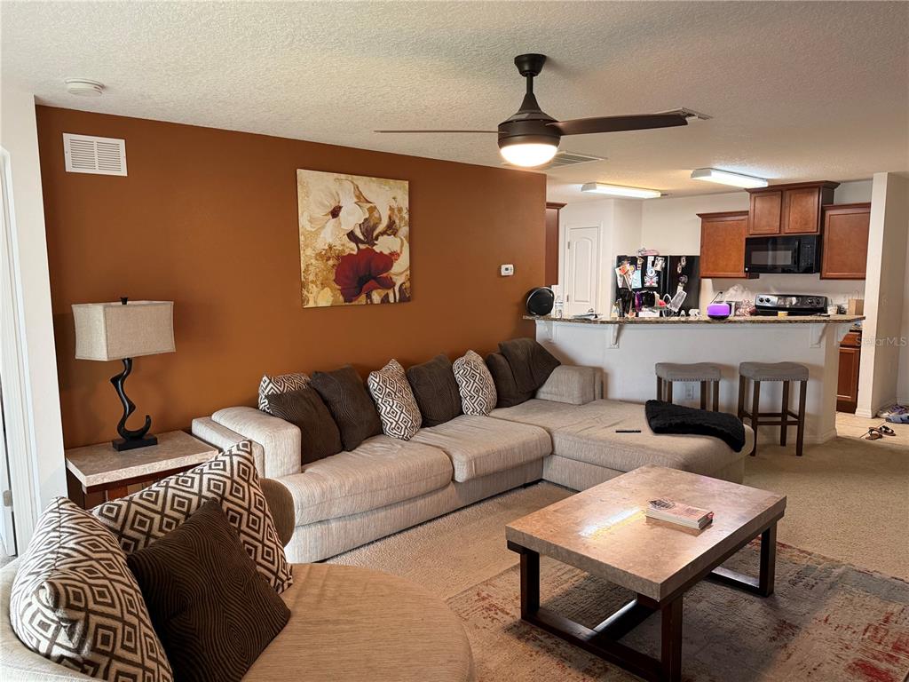 A living room with a sectional sofa, coffee table, and an open kitchen with bar seating — 487 OCHO RIOS AVENUE, TAVARES, FL