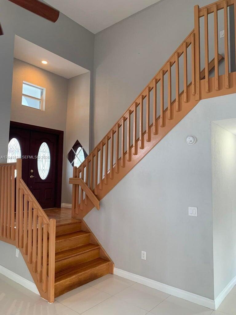 A foyer features a wooden staircase with a railing and a dark front door — 12948 NW 10th St, Miami FL 33182, MIAMI, FL