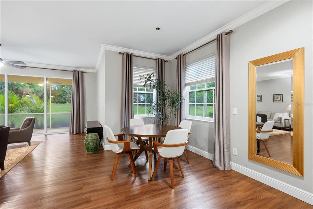 A dining area with a round wooden table, white chairs, and a large gold-framed mirror — 11447 52ND COURT E, PARRISH, FL