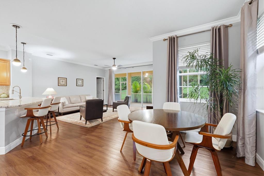 An open-concept living and dining area features wood flooring, a kitchen island, and sliding doors — 11447 52ND COURT E, PARRISH, FL