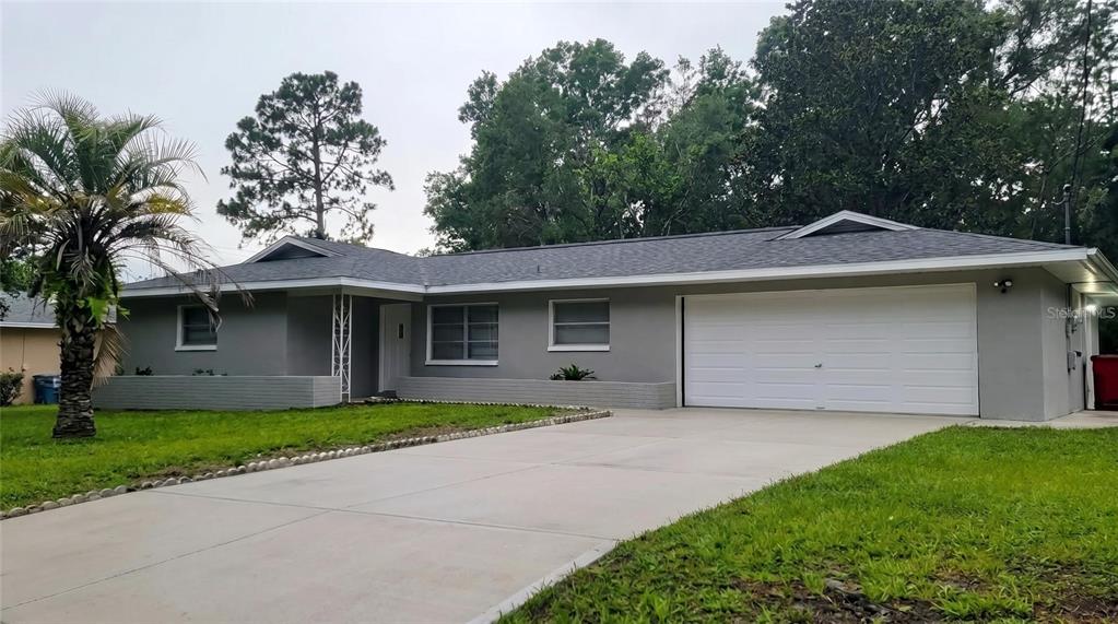 A single-story gray house with a white garage door and a concrete driveway — 3820 S ALPINE AVENUE, INVERNESS, FL