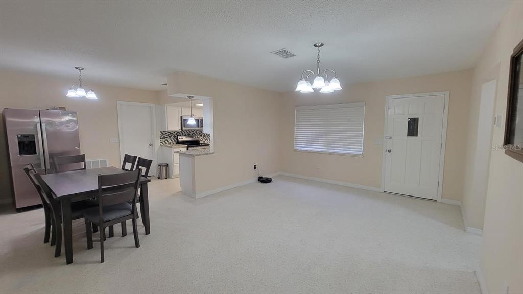 A dining area with a table and chairs sits adjacent to a kitchen and entryway — 3820 S ALPINE AVENUE, INVERNESS, FL