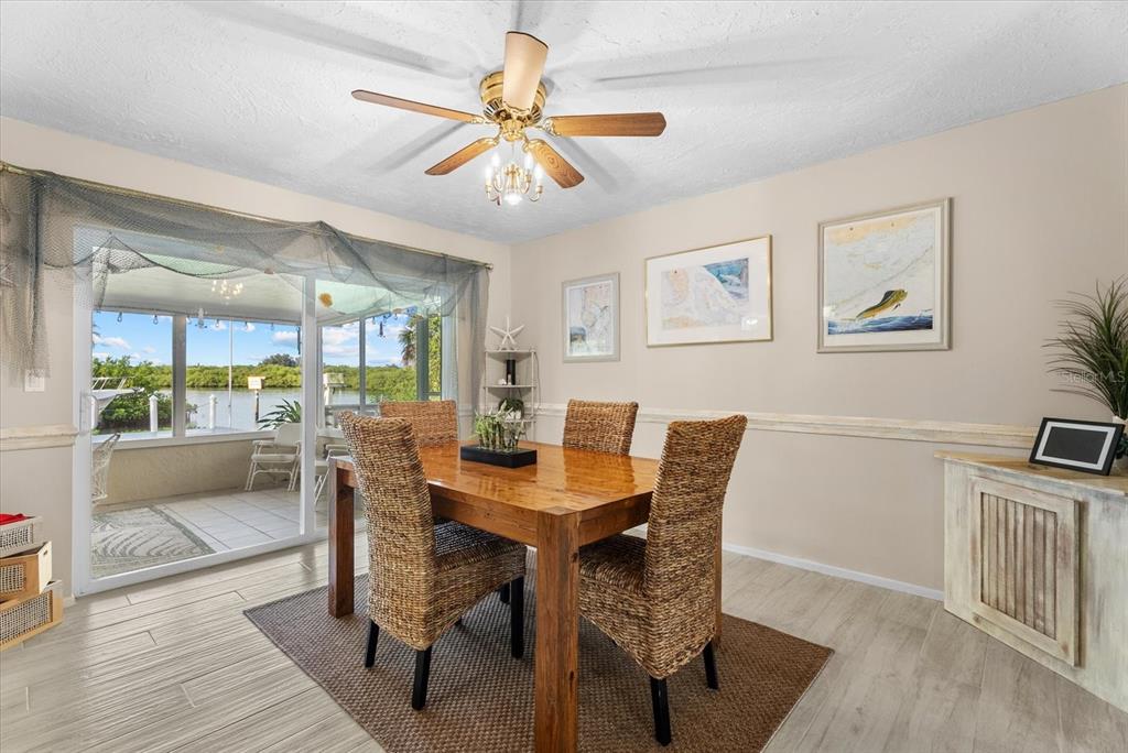 A dining room features a wooden table, woven chairs, a ceiling fan, and sliding glass doors — 5206 18TH AVENUE E, BRADENTON, FL