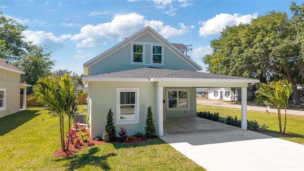 A light green two-story house with a front carport and a landscaped front yard — 25 EDWARDS STREET, PLANT CITY, FL