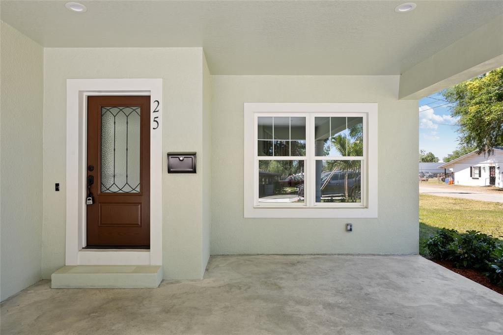 A covered concrete porch features a brown front door with glass and a large window — 25 EDWARDS STREET, PLANT CITY, FL