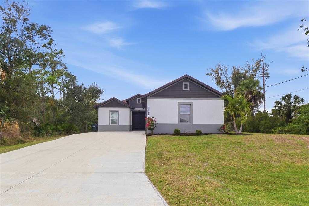 A single-story house with a white and gray exterior features a concrete driveway and lawn — 3373 EAGLE PASS STREET, NORTH PORT, FL