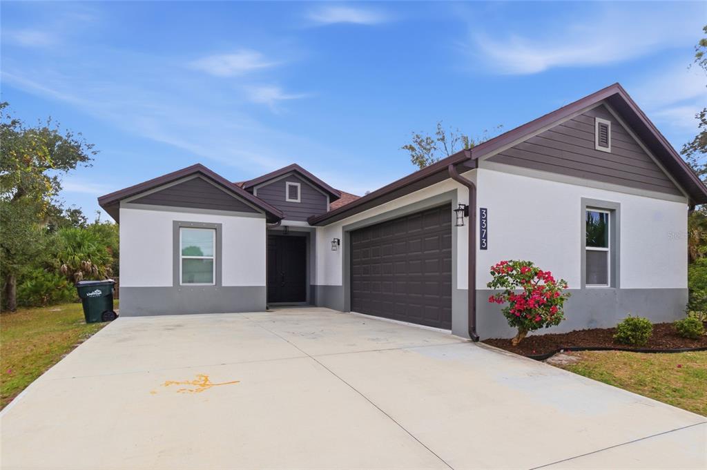 A single-story house with a white stucco facade, dark trim, and a two-car garage — 3373 EAGLE PASS STREET, NORTH PORT, FL