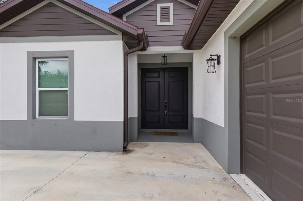The exterior view shows a house entrance with a double door, window, and garage door — 3373 EAGLE PASS STREET, NORTH PORT, FL