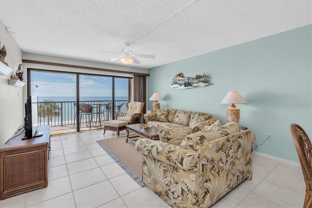 A living room with tile floors, floral furniture, and a balcony overlooking the ocean — 14950 GULF BOULEVARD UNIT 402, MADEIRA BEACH, FL