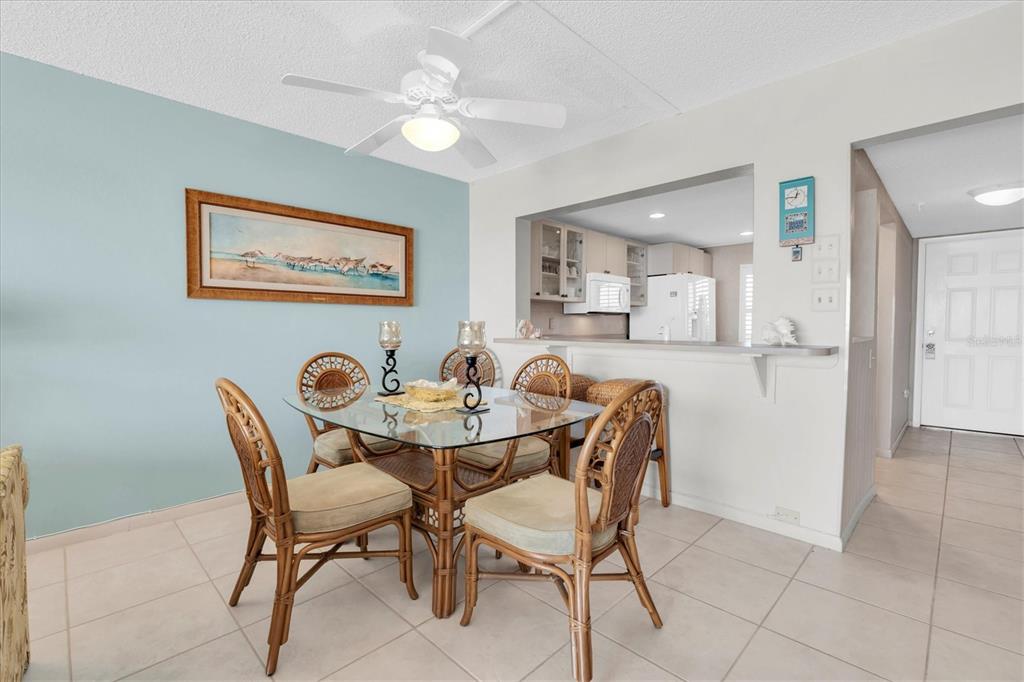 A dining area with a glass table, rattan chairs, and a light blue accent wall — 14950 GULF BOULEVARD UNIT 402, MADEIRA BEACH, FL