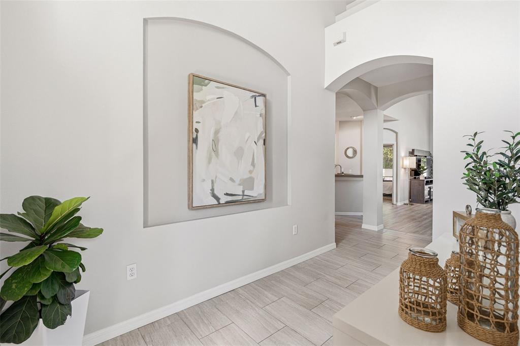 A bright entryway features light tile floors, an arched wall niche, and a large painting — 11809 ACORN WOODS TERRACE, LAKEWOOD RANCH, FL