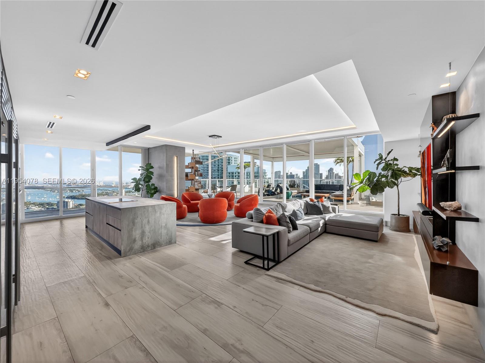 A modern open-concept living area features a kitchen island, gray sectional, and orange accent chairs — 2020 N Bayshore Dr # 4104, Miami FL 33137, MIAMI, FL