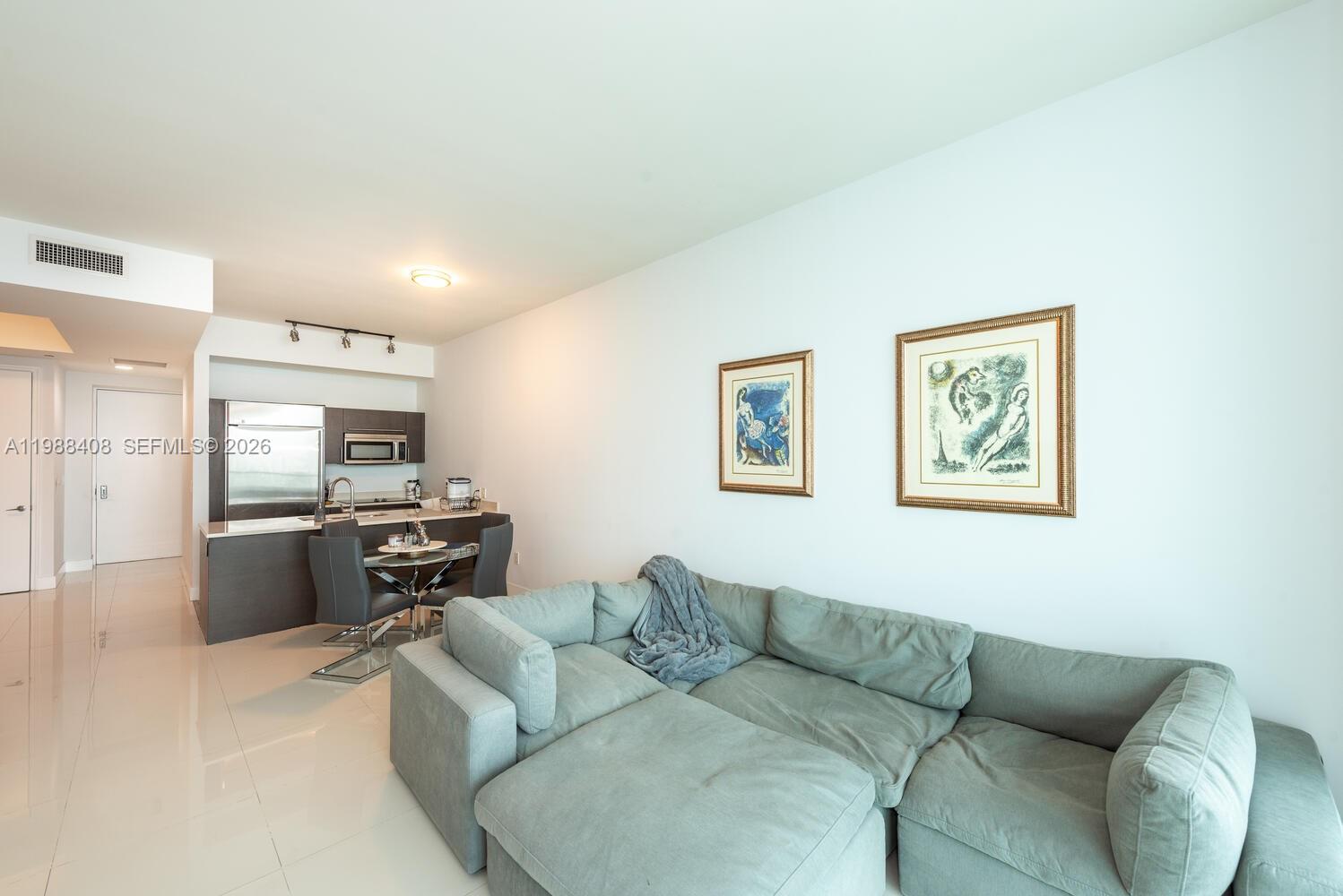 A living room with a light blue sectional sofa and an adjacent open kitchen area — 55 SE 6th St # 4200, Miami FL 33131, MIAMI, FL