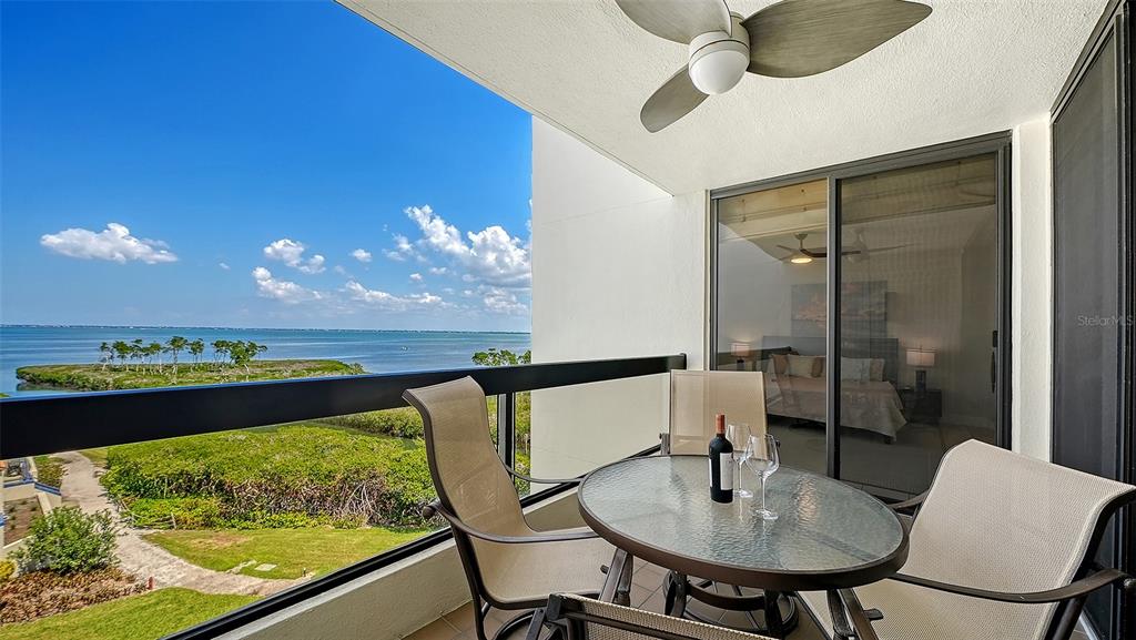 A balcony with a glass-topped table, chairs, and a view of the water — 1932 HARBOURSIDE DRIVE UNIT 242, LONGBOAT KEY, FL