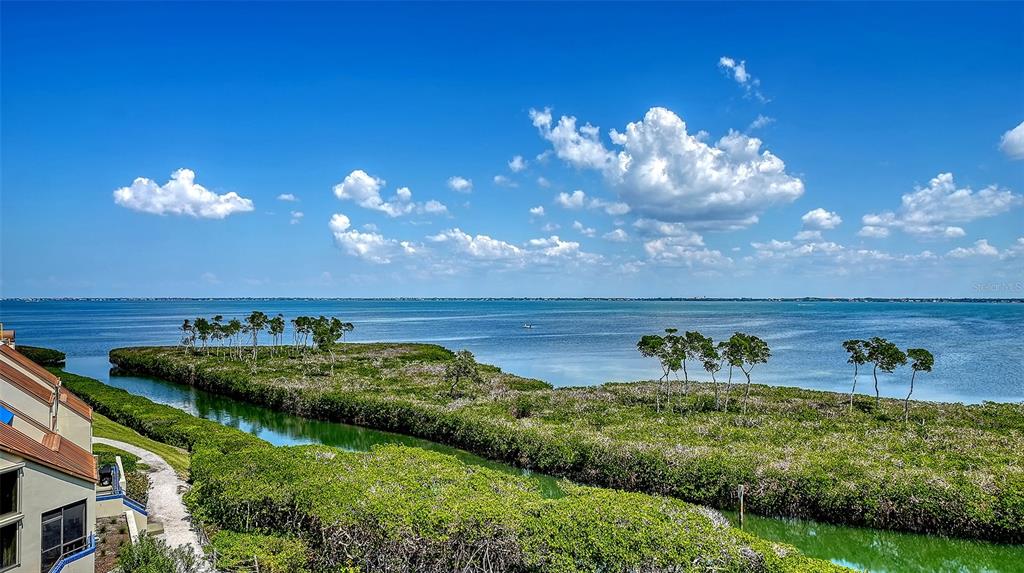 An elevated view of a coastal inlet with mangroves and a building exterior — 1932 HARBOURSIDE DRIVE UNIT 242, LONGBOAT KEY, FL
