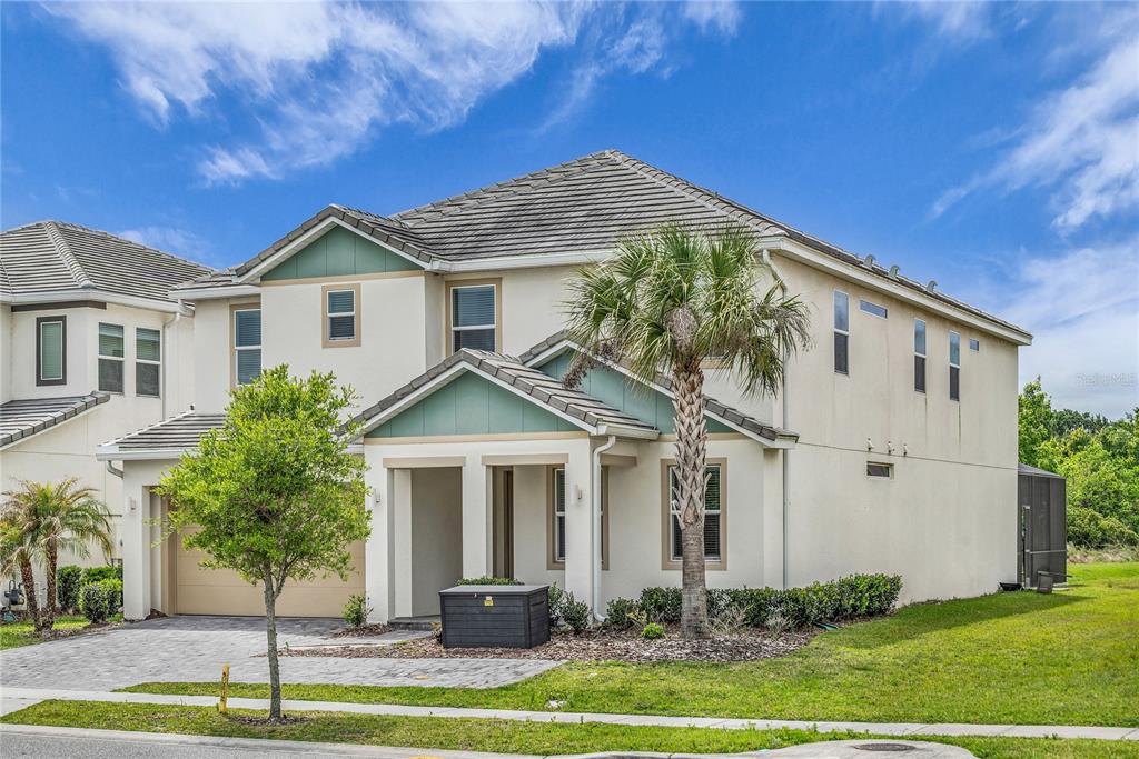 A two-story suburban house with a tan stucco exterior, teal accents, and a palm tree — 2576 SHANTI DRIVE, KISSIMMEE, FL