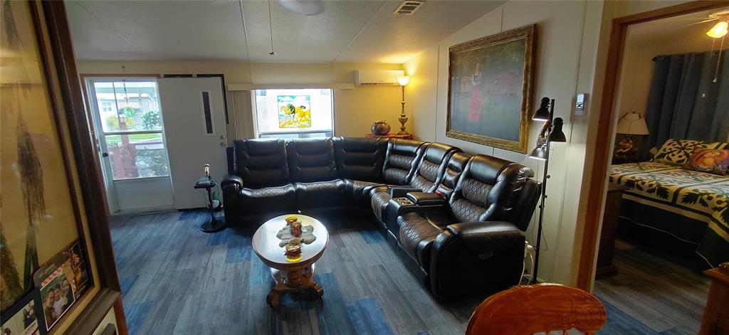 A living room features a large black sectional sofa, a coffee table, and wood-look flooring — 221 HERON ROAD, CLEARWATER, FL
