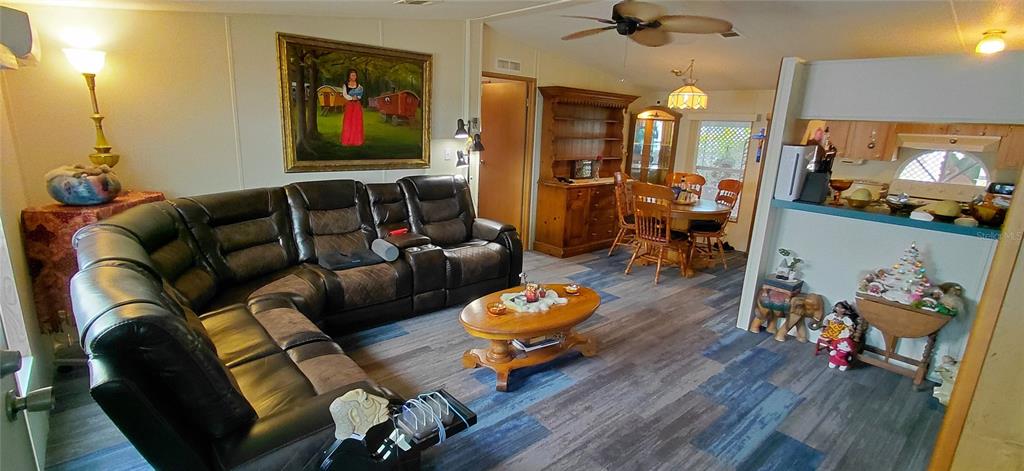 A living room features a large dark leather sectional, a wooden coffee table, and dining area — 221 HERON ROAD, CLEARWATER, FL