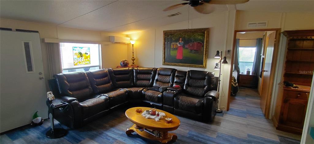 A living room features a large dark leather sectional, a wooden coffee table, and artwork — 221 HERON ROAD, CLEARWATER, FL