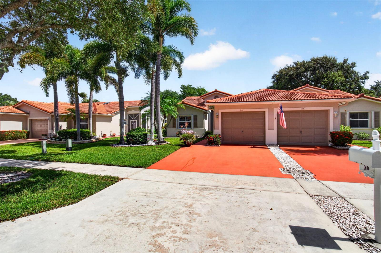A street-level view of a suburban house with a red driveway and palm trees — 26 Sausalito Drive, Boynton Beach FL 33436, BOYNTON BEACH, FL