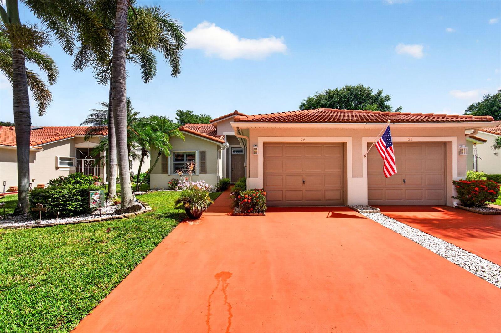 A single-story duplex with a red-painted driveway, two garage doors, and a tiled roof — 26 Sausalito Drive, Boynton Beach FL 33436, BOYNTON BEACH, FL