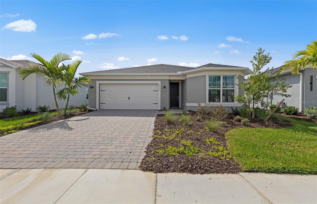 A single-story gray house features a paved driveway, a two-car garage, and front landscaping — 16335 LILLY ELAINE WAY, BRADENTON, FL