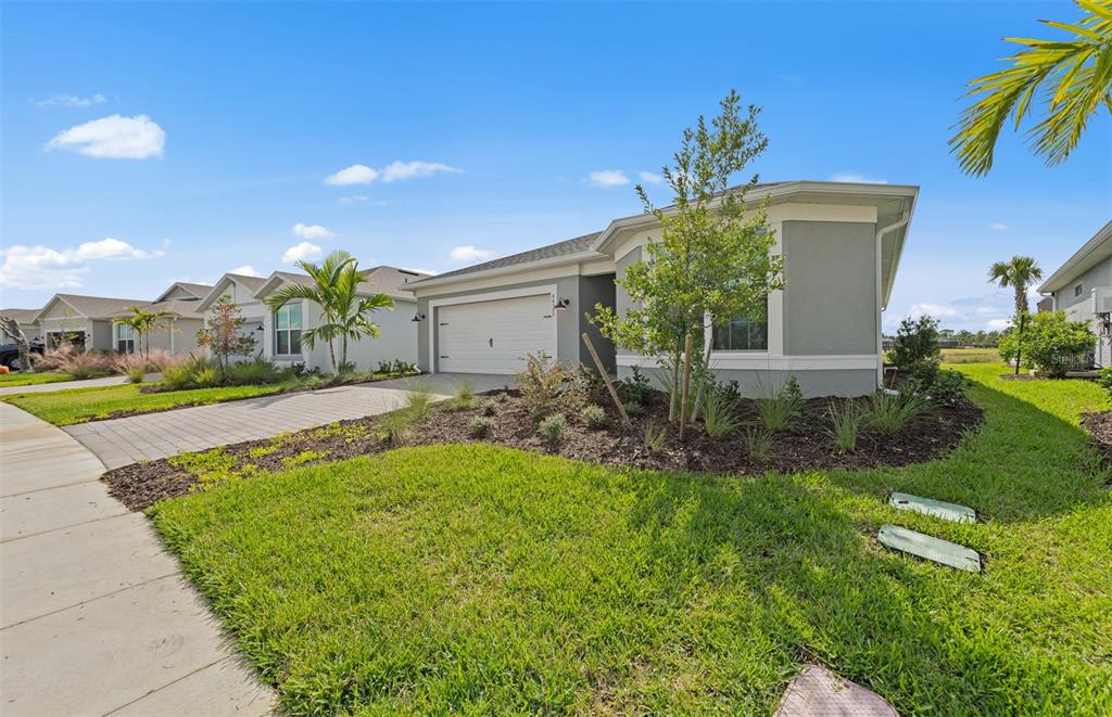 A single-story house with a gray exterior, a two-car garage, and a landscaped front yard — 16335 LILLY ELAINE WAY, BRADENTON, FL