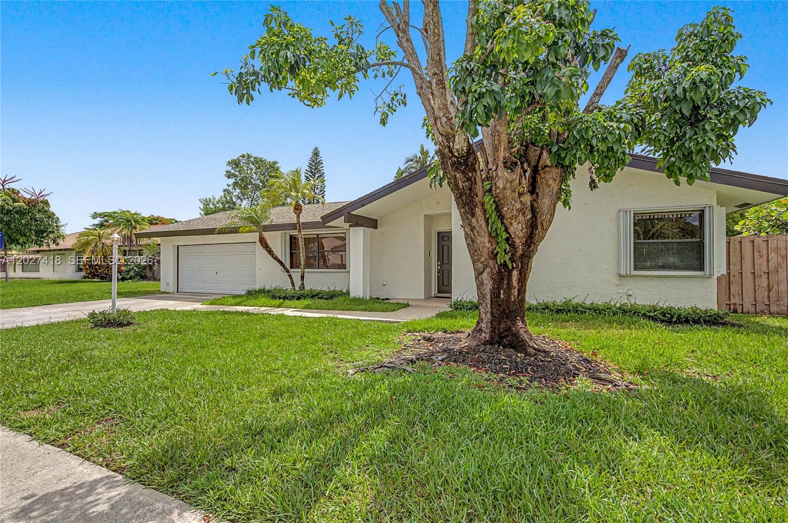 A single-story white house with a garage, a large front tree, and a grassy lawn — 10711 SW 116th Ave, Miami FL 33176, MIAMI, FL