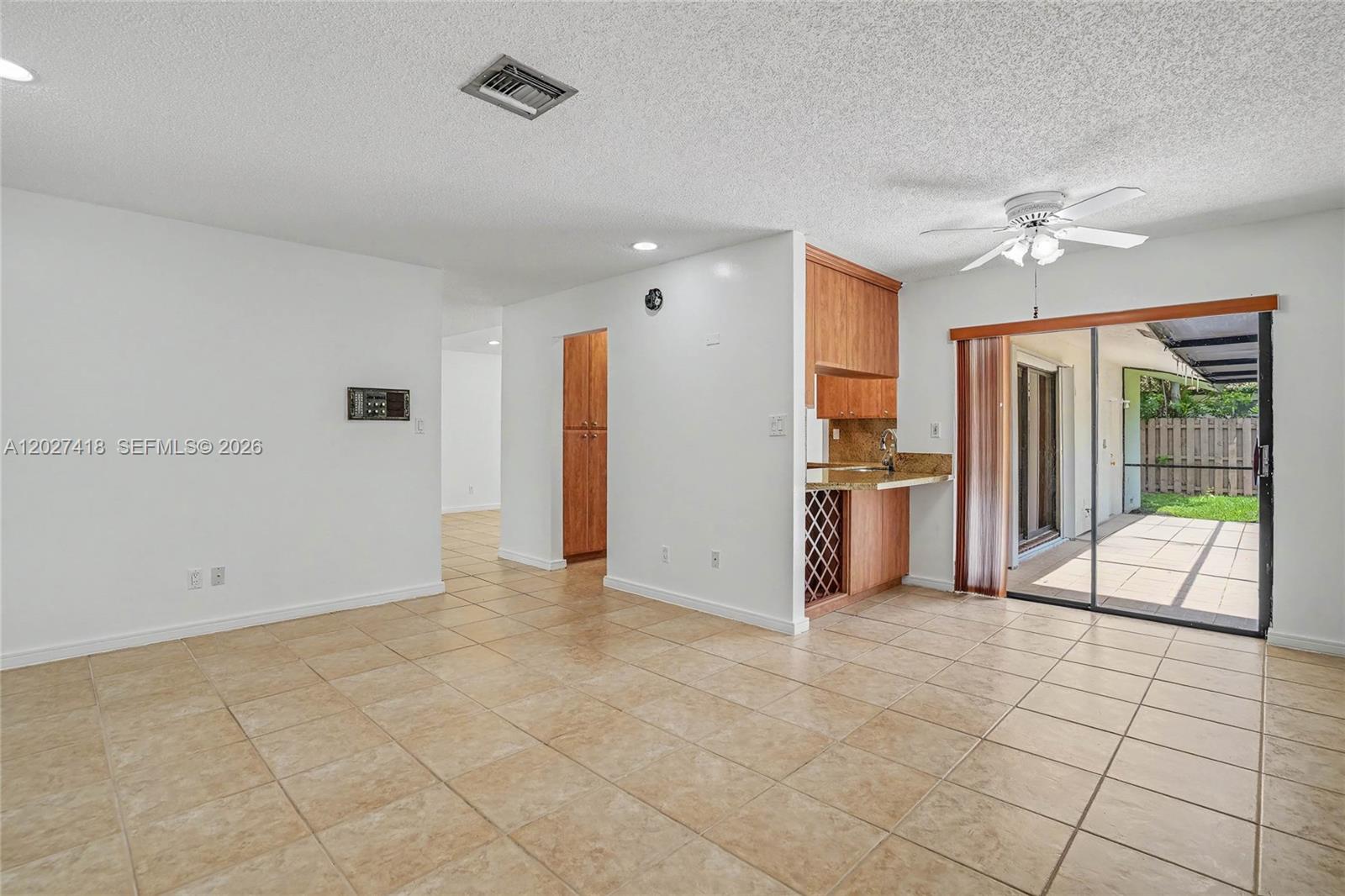 A tiled living area features a small kitchen nook and a sliding door to a patio — 10711 SW 116th Ave, Miami FL 33176, MIAMI, FL