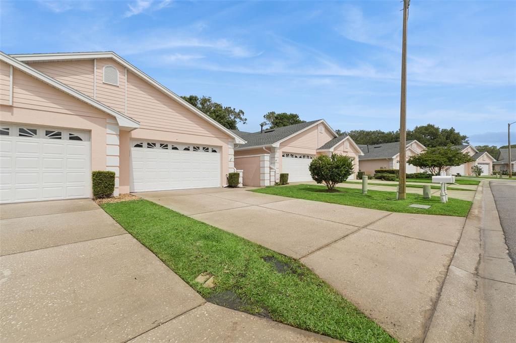 A row of light pink single-story houses with white garage doors and concrete driveways — 10 ENCLAVE DRIVE, WINTER HAVEN, FL