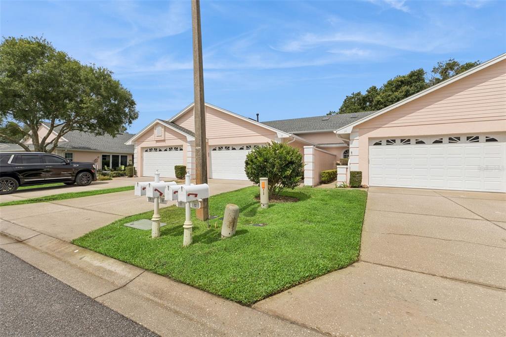 A row of attached houses with light pink siding and white garage doors under a blue sky — 10 ENCLAVE DRIVE, WINTER HAVEN, FL
