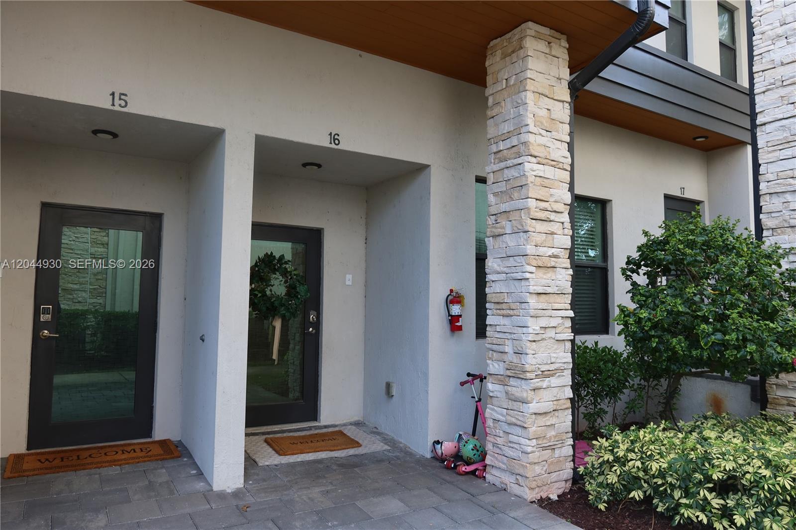 The exterior view shows three adjacent townhouse entrances with stone columns and modern glass doors — 10467 NW 82nd St # 16, Doral FL 33178, DORAL, FL