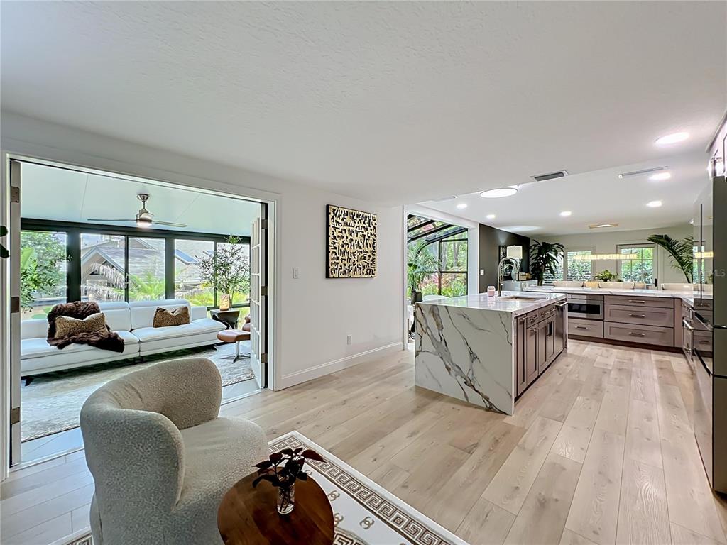 A modern kitchen features marble countertops, a waterfall island, and gray cabinetry — 128 WOODMILL ROAD, LONGWOOD, FL