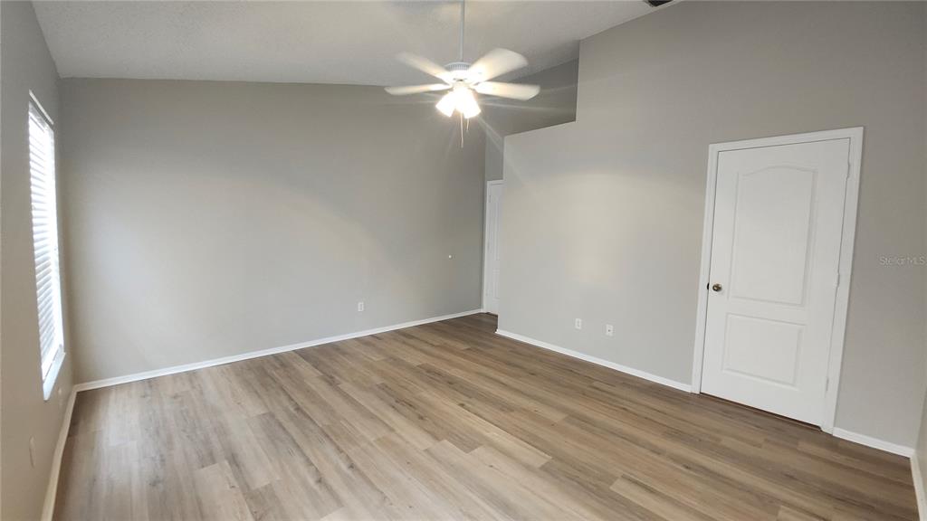 A room with light gray walls, wood-look flooring, a ceiling fan, and a white door — 12507 MIDPOINTE DRIVE, RIVERVIEW, FL